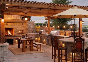Captivating-Outdoor-Kitchen-with-Stone-Fireplace-Wooden-Dining-Table-Good-Lighting-and-Patio-Umbrella