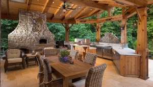 Fancy-Outdoor-Kitchen-Design-with-Wooden-Dining-Table-Wicker-Chairs-and-Stone-Fireplace