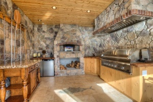 Outdoor-Kitchen-Design-with-Natural-Stone-Wall-Fireplace-Teak-Wood-Cabinets-and-Granite-Worktop